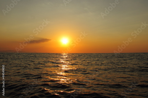 Orange bright sunset under the ocean. Sun reflection on water scenic, yellow dusk, peaceful nature landscape © Olga