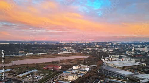 Aerial drone view of Chisinau at sunset. Panorama view of industrial zone, residnetial buildings, lake, bare trees. Rose clouds photo