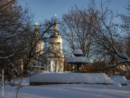 fountain under snow and church behind