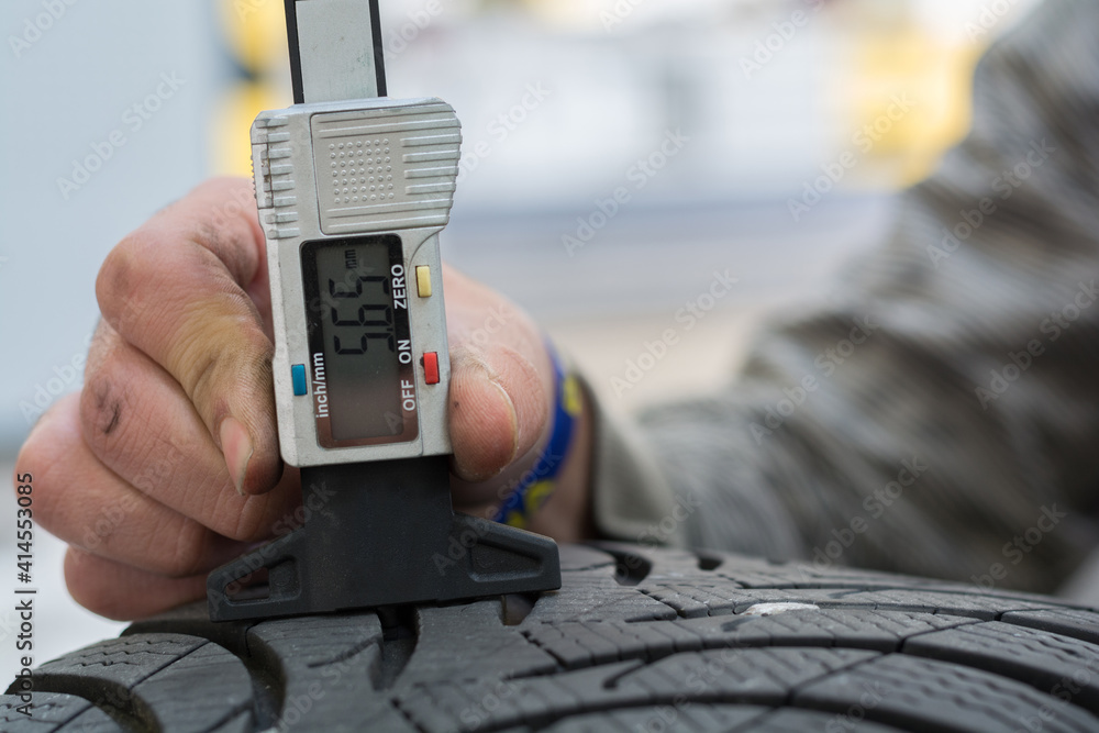 Person With Tread Depth Gauge Measures The Tread Depth Of Tires