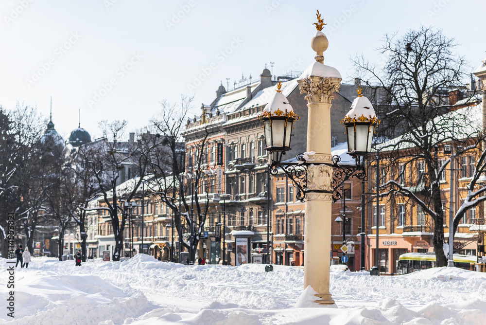 LVIV, UKRAINE - FEBRUARY 12, 2021: Ancient street lantern near Lviv Theatre of Opera and Ballet, winter time.