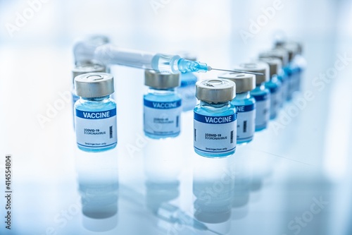 Ampoules with Covid-19 vaccine on a laboratory bench. Syringe with needle.