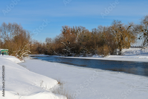 Winter landscape with frozen river with vibrant blue sky on a bright sunny day.