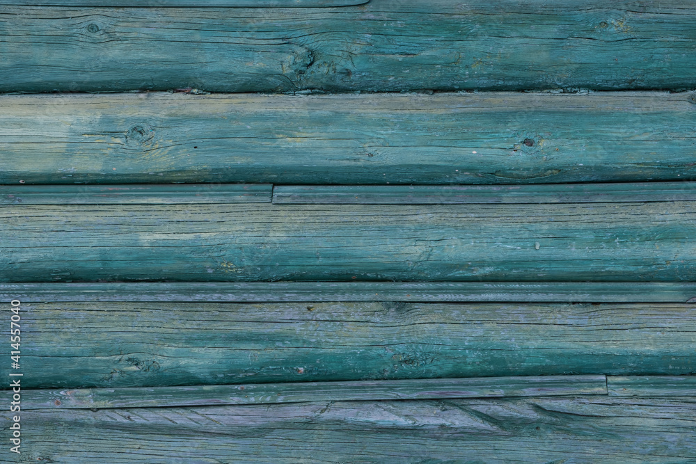 An old wall of pine logs. Weathered, faded wood. Green paint faded in the sun. Factura of a tree. An old wall of pine logs. Weathered, faded wood. Green paint faded in the sun. Factura of a tree.