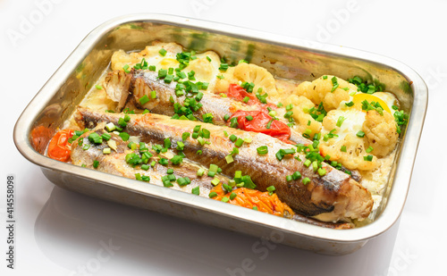 hake fish baked with vegetables close view, baking tray with tomatoes, broccoli and spices, home cooking