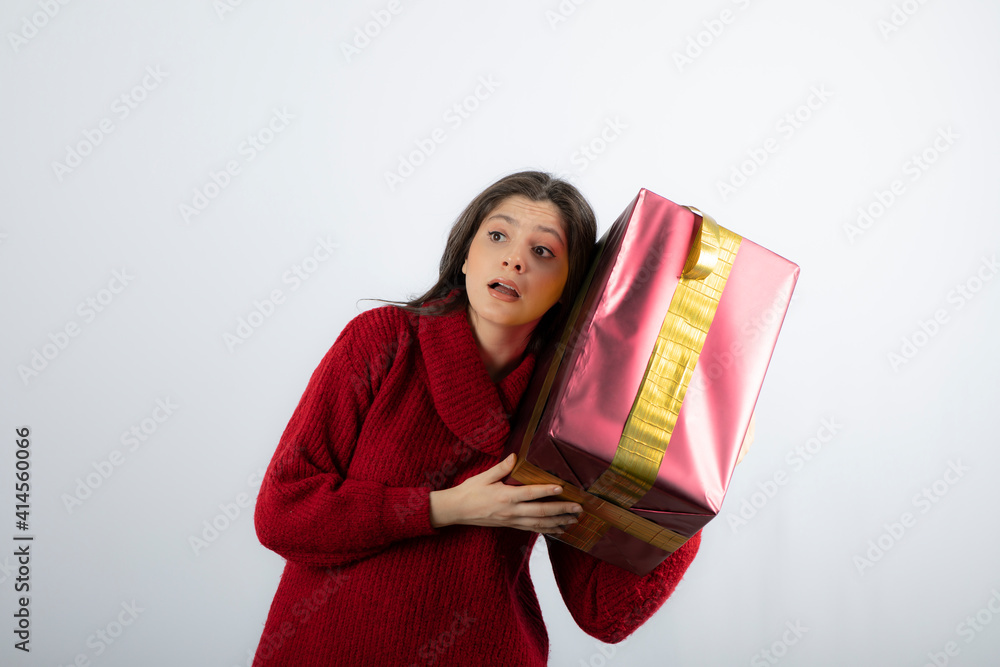 Portrait of a young girl dressed in sweater and holding gift box Portrait of a young girl dressed in sweater and holding gift box