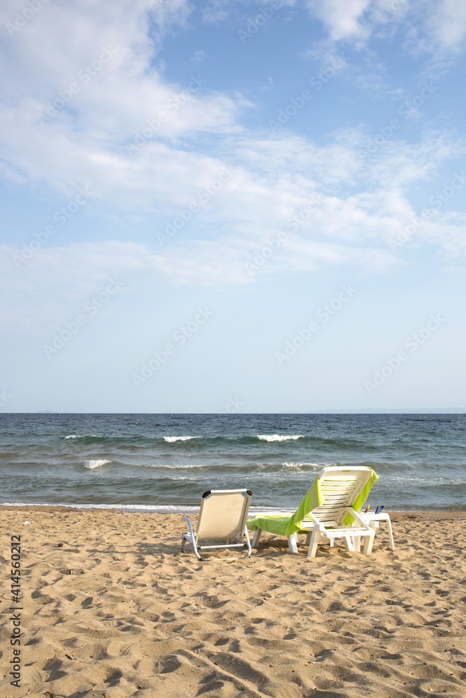 Two beach chairs looking at the sea with waves and beautiful blue sky with clouds.Copy space,text space, flayer,web banner. Two beach chairs looking at the sea with waves and beautiful blue sky with clouds.Copy space,text space, flayer,web banner.