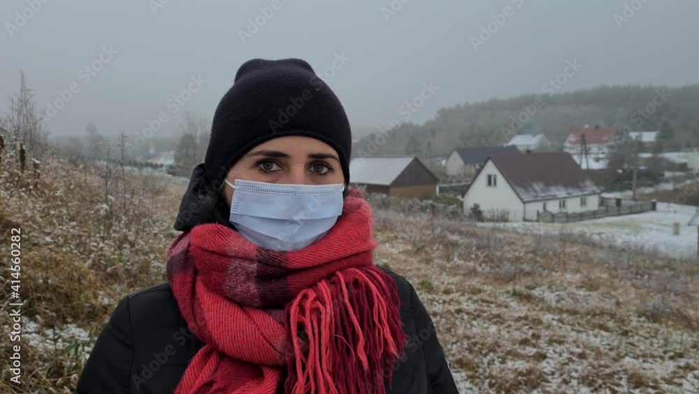 A 40-year-old woman with a protective mask against the coronavirus COVID-19 is in the forest during the winter season and enjoys the fresh air A 40-year-old woman with a protective mask against the coronavirus COVID-19 is in the forest during the winter season and enjoys the fresh air