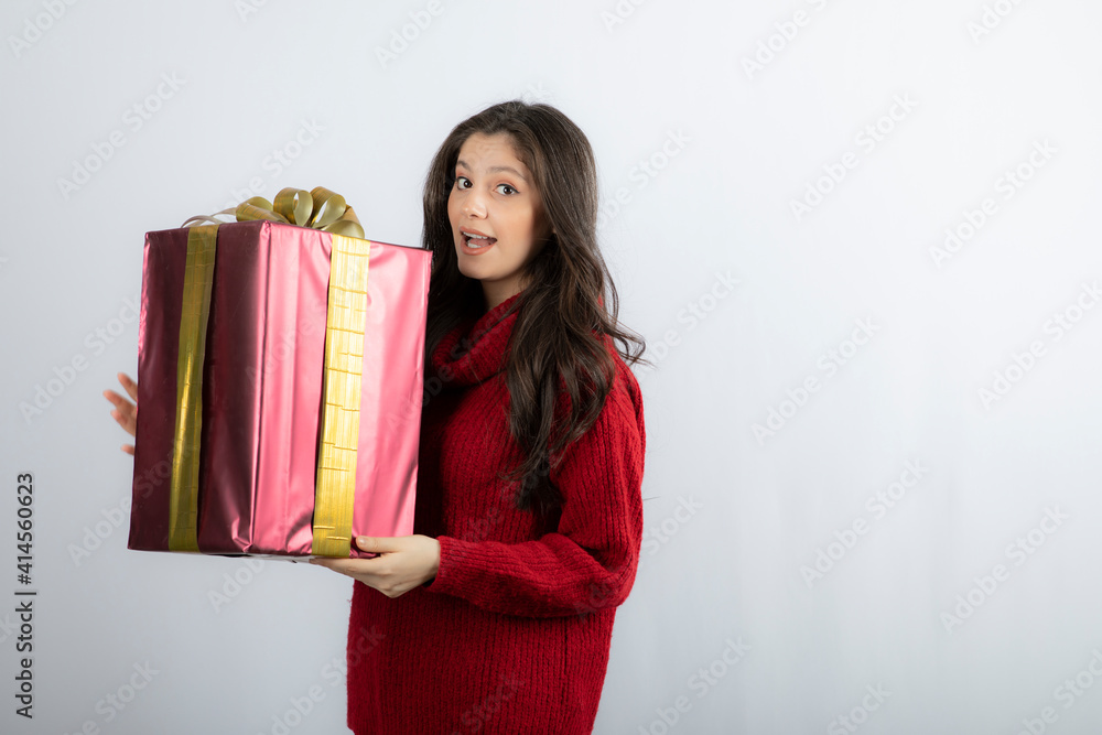 Portrait of a smiling girl in sweater holding present box Portrait of a smiling girl in sweater holding present box