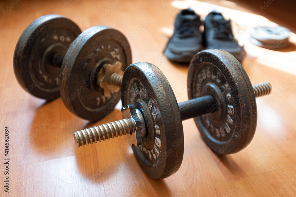 Dumbbells padded from a pair of sneakers on a wooden floor Dumbbells padded from a pair of sneakers on a wooden floor