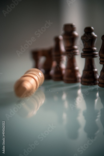 Chess pieces lined up on a table white and black with fallen king representing defeat