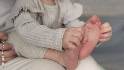 Cute curious pretty little baby playing with legs, counting toes, tickling feet