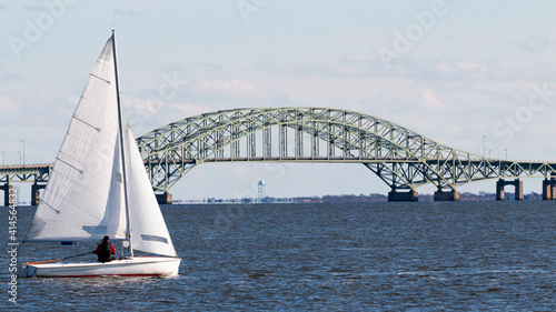 Small sailboat sailing past the great south bay bridge