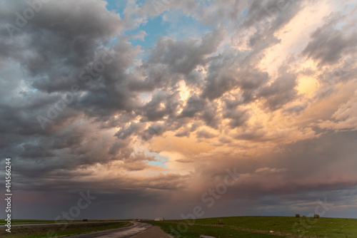 A flat landscape highway seen before a cloudy storm approaching with pink, orange dark clouds, shining sun and dark country, rural land below. Great for sky replacement for editing photos or drawing.  photo