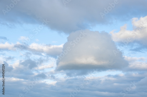 A cloud of a strange and interesting shape against a background of other clouds and a blue sky. Space for text.