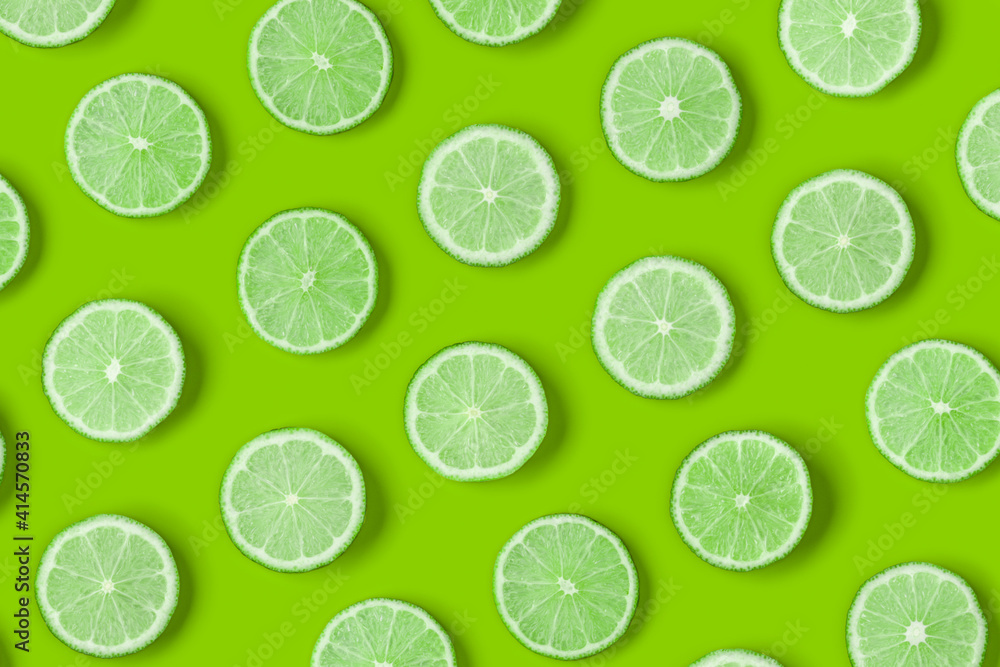 Fruit pattern of lime slices on green background. Flat lay, top view.