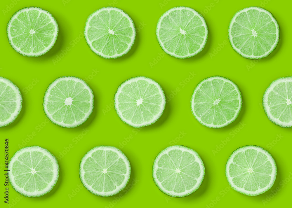 Fruit pattern of lime slices on green background. Flat lay, top view. Seamless pattern.