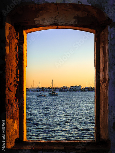 Vila Real de Santo Antònio (Portugal), seen from Ayamonte (Spain), with the Guadiana river and the sailboats in foreground, seen through the window opening