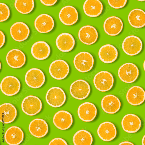 Fruit pattern of orange slices on green  background. Flat lay, top view. Food background.