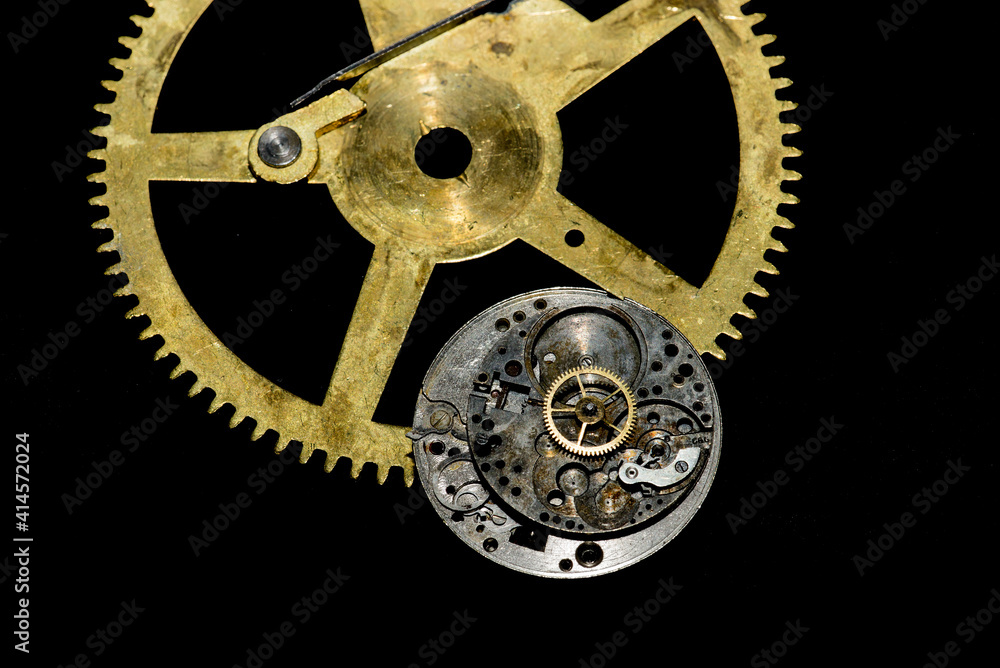 Obraz premium Closeup of antique watch parts in gold and silver on black needing repair.