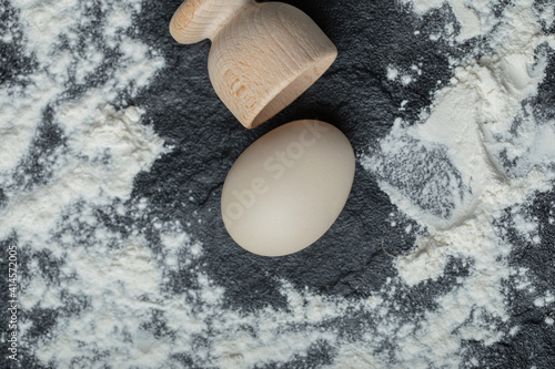 close up photo of Egg cup and raw egg on floury background photo