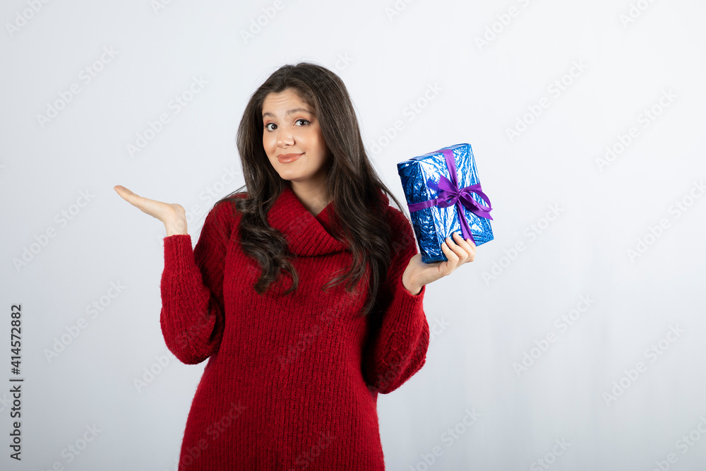 Portrait of a smiling woman holding a Christmas gift box with purple ribbon Portrait of a smiling woman holding a Christmas gift box with purple ribbon