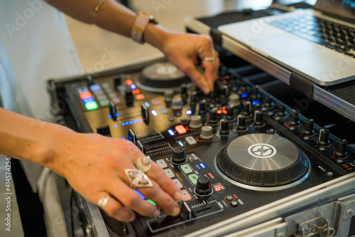 A female DJ with jewellery on her fingers pressing buttons and mixing on a turntable