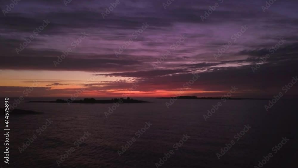 Aerial flyover calm ocean with breathtaking sunset in background. Cloudscape and silhouette of island. Aerial flyover calm ocean with breathtaking sunset in background. Cloudscape and silhouette of island.