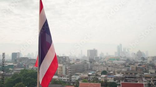 4k Slow motion waving Thai flag. Thailand state flag fluttering in the wind on the top of Wat Saket Golden Mountain. Bangkok panorama view on background, Rooftop of Wat Saket Temple photo