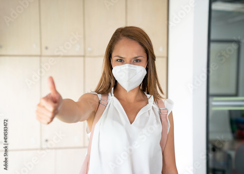 Positive student using a facemask with thumb up at university.