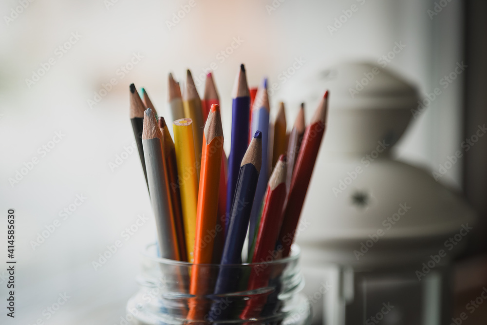 Set of colored wooden pencils in glass cup, blurred background Set of colored wooden pencils in glass cup, blurred background