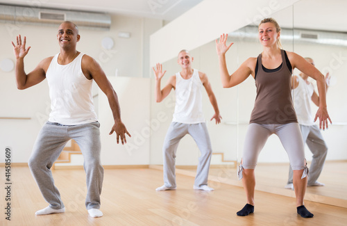 Group of happy adult people training movements of modern dance in choreography class
