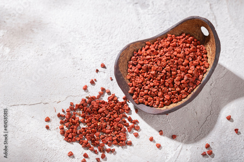 achiote grains in wooden bowl on white background (Bixa orellana) photo