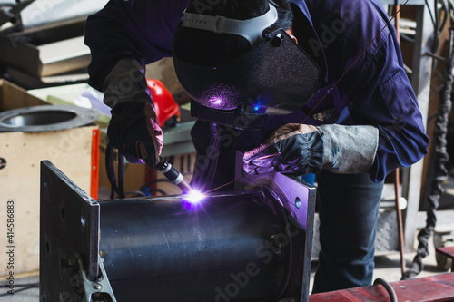 Welder is welding the steel in the factory.