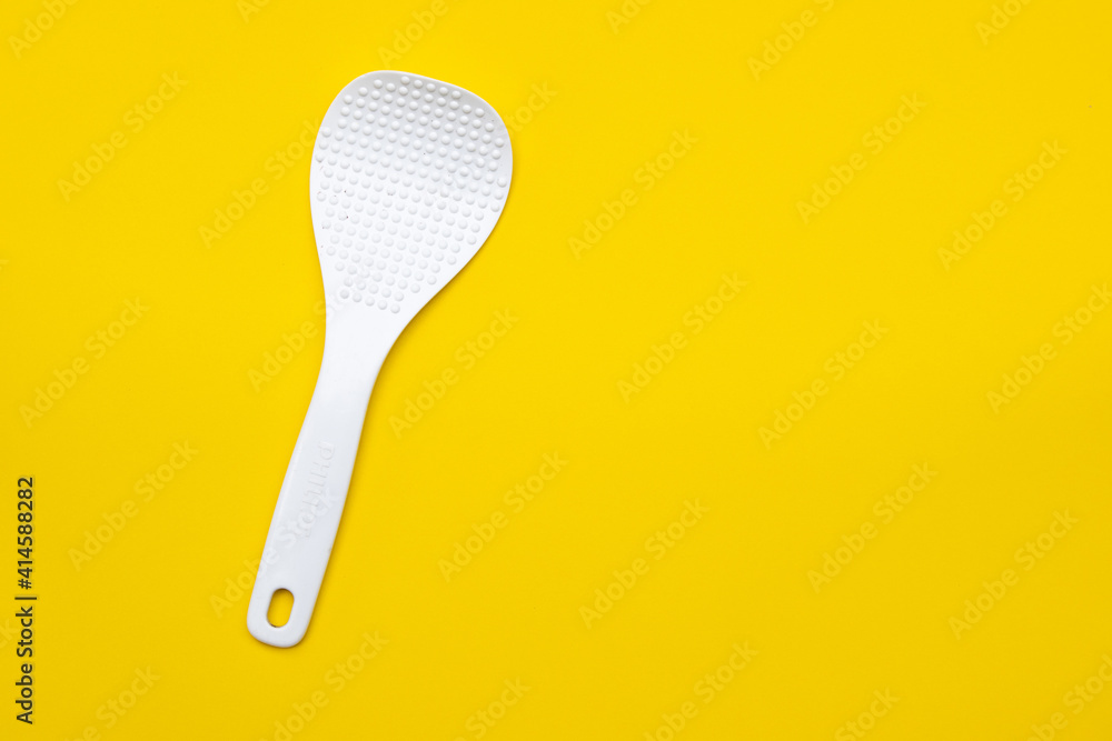 White plastic ladle on yellow background with copy space White plastic ladle on yellow background with copy space