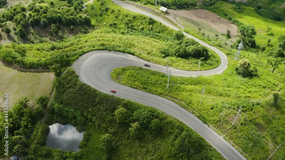 Aerial view flying over road with car moving, country road in rural rolling hills. Car driving along the forest road. Aerial view flying over road with car moving, country road in rural rolling hills. Car driving along the forest road.