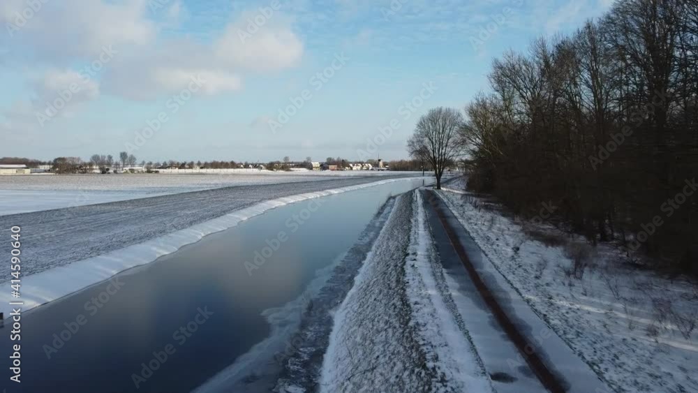 Dutch winter landscape. Frozen ditch, snow on the farmland. Dutch village in the distance. Dutch winter landscape. Frozen ditch, snow on the farmland. Dutch village in the distance.