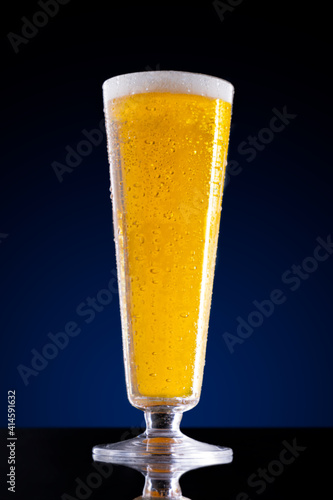Tall glass of beer on a blue background