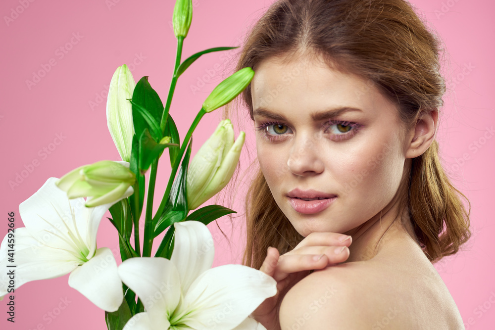 Portrait of woman with white flowers beautiful face pink background naked shoulders