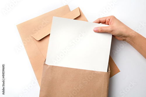 Female hands holding brown paper envelope with blank white paper.