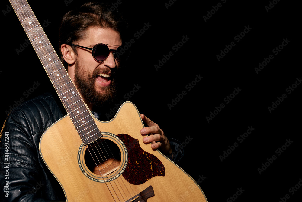 Obraz premium A man with a guitar in his hands leather jacket music performance rock star modern style dark background