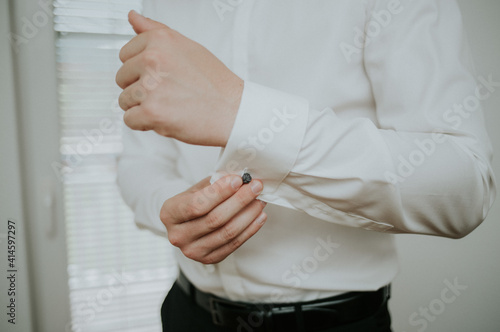 Canvas Print Closeup of a stylish and elengant man adjusting the cufflink on his white formal