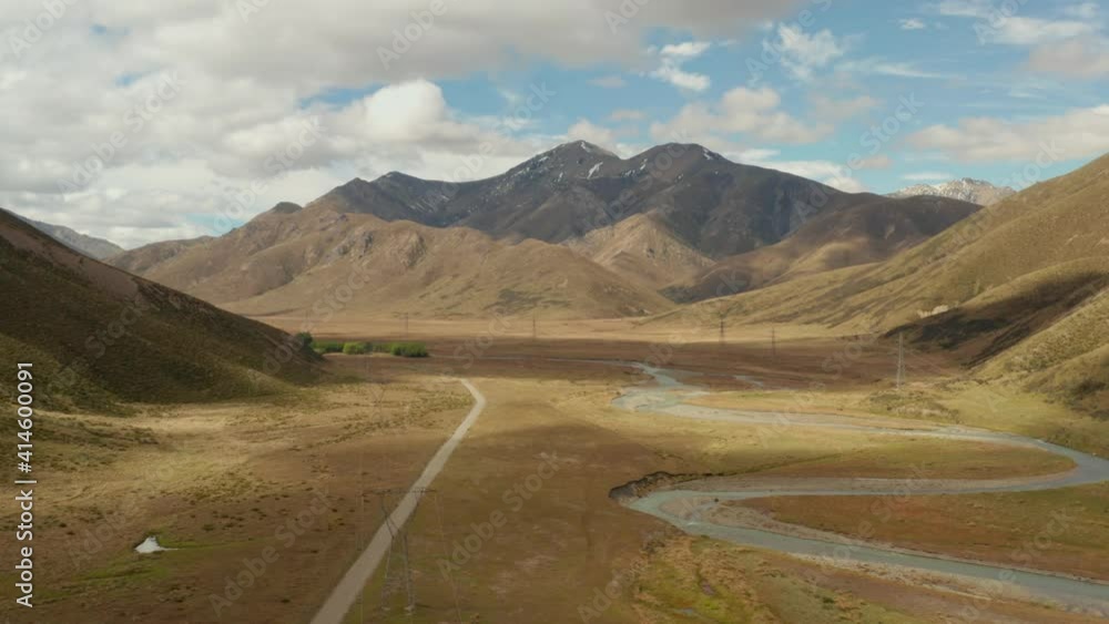 Drone view of a valley in New Zealand with a winding river and high voltage towers.