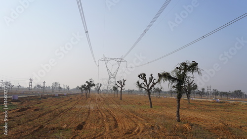 Desolate empty fields with Three phase power supply lines. Wire trap leads to horizon with blue sky nature.