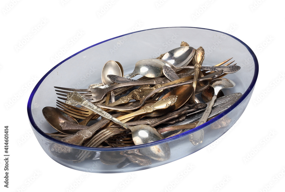 Old silver spoons and forks in a glass plate isolated