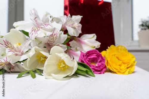 composition of a gift package and a bouquet of flowers. holiday and congratulations concept