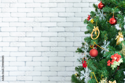 Closeup of beautiful little Chrsitmas baubles as red and golden glass ball is hanging on Christmas tree branches in front of grey wall in living room in holidays as Christmas eve or new years. 