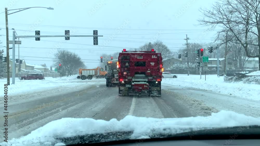 Positioned behind a snow plow at a traffic light on a snowy day. Positioned behind a snow plow at a traffic light on a snowy day.