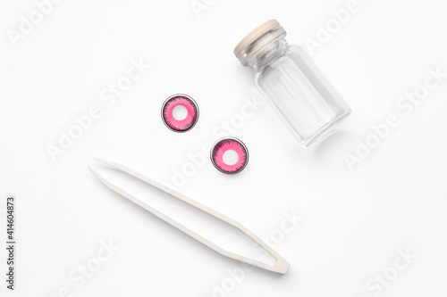 Tweezers, color contact lenses and bottle on white background