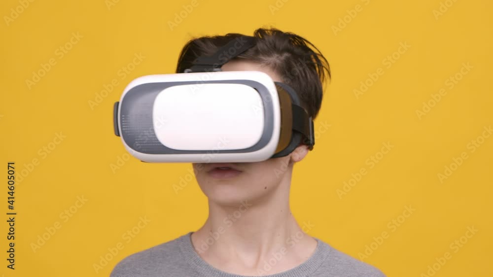 Boy Wearing VR Headset Experiencing Virtual Reality, Yellow Background Boy Wearing VR Headset Experiencing Virtual Reality, Yellow Background